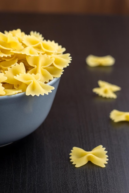 Zwarte achtergrond met italiaanse rauwe farfalle of pasta in kom met kopieerruimte