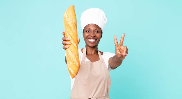 Zwarte afrikaanse amerikaanse volwassen chef-kokvrouw die een broodbaguette houdt