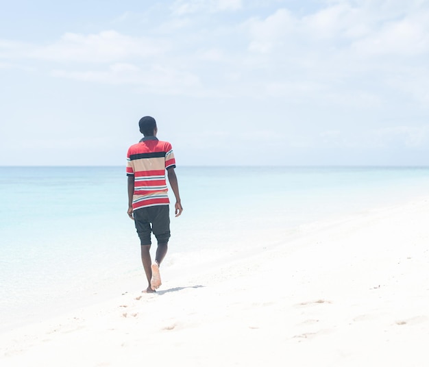 Zwarte Afrikaanse jonge man lopen op tropisch strand