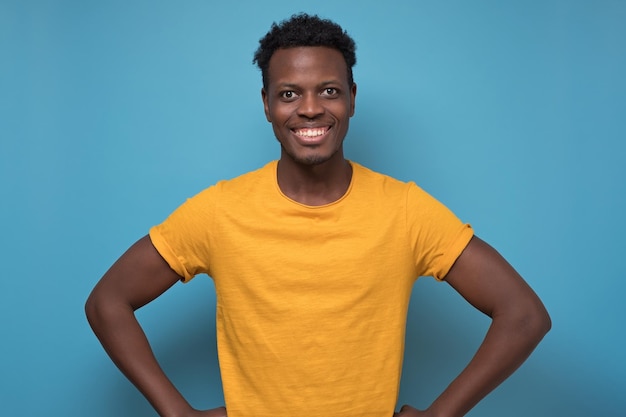 Zwarte Afro-Amerikaanse jongeman in gele t-shirt met vrolijke houding