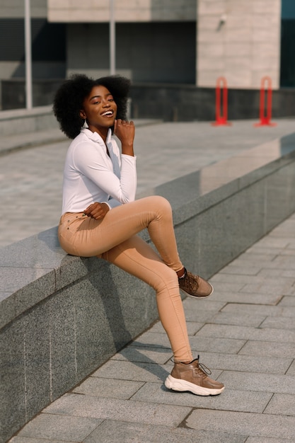 Zwarte Afro-Amerikaanse student zit in de stad en glimlacht