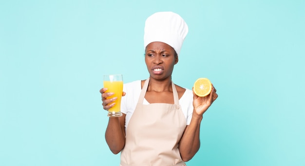 Zwarte Afro-Amerikaanse volwassen chef-kok vrouw. sinaasappelsap concept