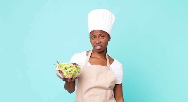 zwarte afro-amerikaanse volwassen chef-kokvrouw die een salade houdt