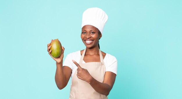 Zwarte Afro-Amerikaanse volwassen chef-kokvrouw met een mango