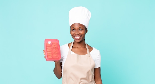 Zwarte Afro-Amerikaanse volwassen chef-kokvrouw met een tupperware