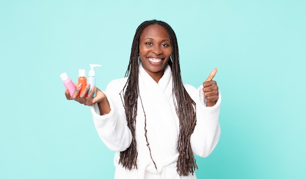 Zwarte Afro-Amerikaanse volwassen vrouw die een badjas draagt en cosmetische producten vasthoudt