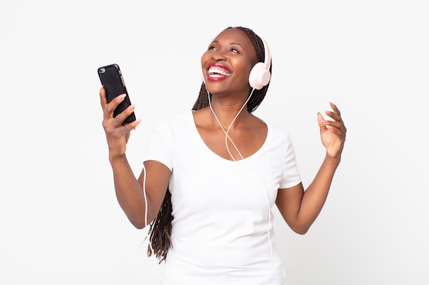 Zwarte Afro-Amerikaanse volwassen vrouw die muziek luistert met koptelefoon en smartphone