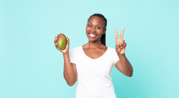 Zwarte Afro-Amerikaanse volwassen vrouw met een mangofruit