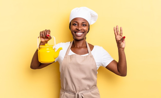 Zwarte afro-chef-vrouw lacht en ziet er vriendelijk uit, nummer drie of derde met hand naar voren, aftellend. theepot concept