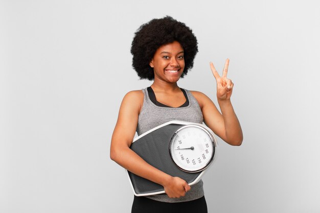 Zwarte afro fitness vrouw met een weegschaal of weegschaal