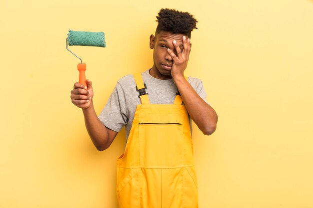 Zwarte afro jonge man verveeld, gefrustreerd en slaperig na een vermoeiende huishoudster die naar huis schildert