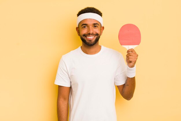 Zwarte afro-man die gelukkig lacht met een hand op de heup en zelfverzekerd pingpongconcept