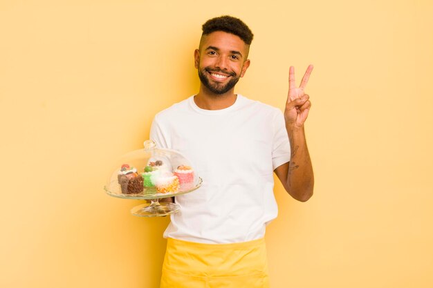 Zwarte afro man die lacht en er vriendelijk uitziet met nummer twee zelfgemaakte taarten concept