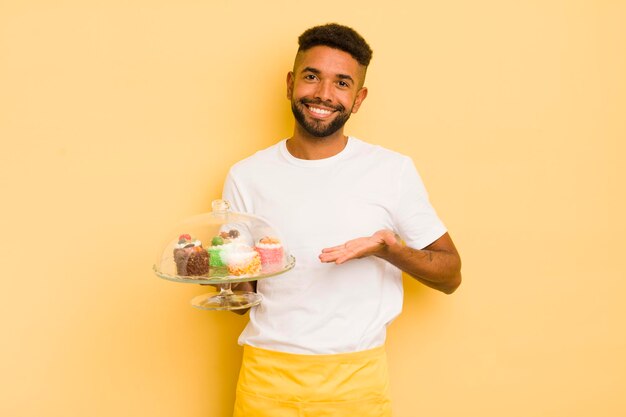 Zwarte afro-man die vrolijk lacht en zich gelukkig voelt en een concept voor zelfgemaakte taarten toont