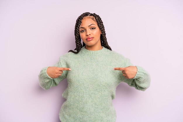 Zwarte afro-vrouw die er trots, positief en casual uitziet en met beide handen naar de borst wijst