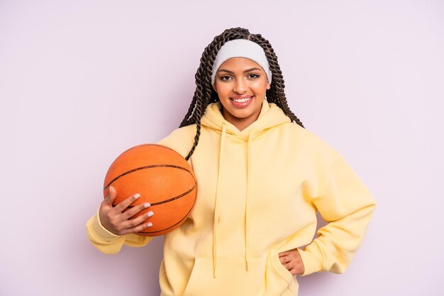 Zwarte afro vrouw die gelukkig lacht met een hand op de heup en zelfverzekerd. basketbal concept