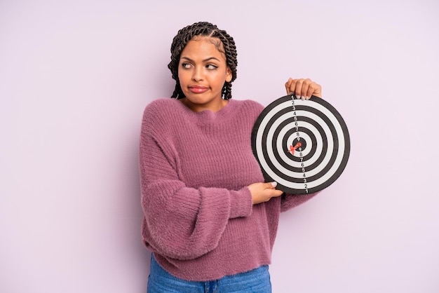 Zwarte afro-vrouw die haar schouders ophaalt, zich verward en onzeker voelt. doel dart concept