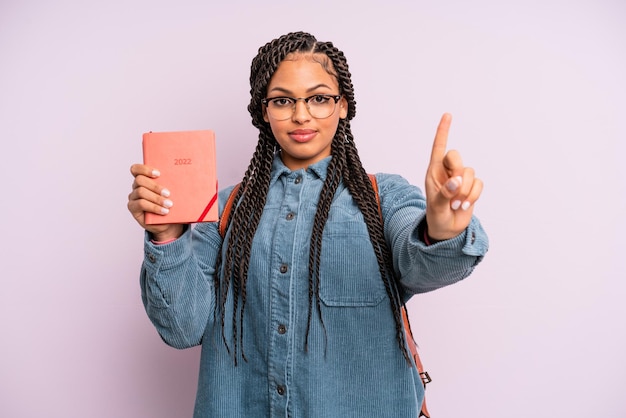 Zwarte afro-vrouw die lacht en er vriendelijk uitziet, met nummer één. studentenkalender of agendaconcept