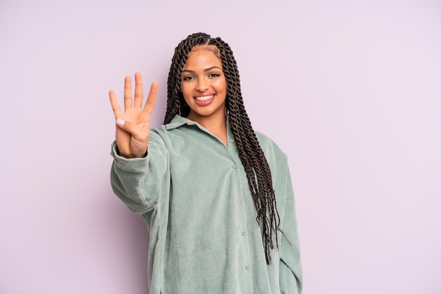 Zwarte afro-vrouw die lacht en er vriendelijk uitziet, nummer vier of vierde toont met de hand naar voren, aftellend