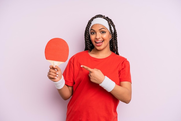 Zwarte afro-vrouw die opgewonden en verrast kijkt en naar de zijkant wijst. pingpongconcept