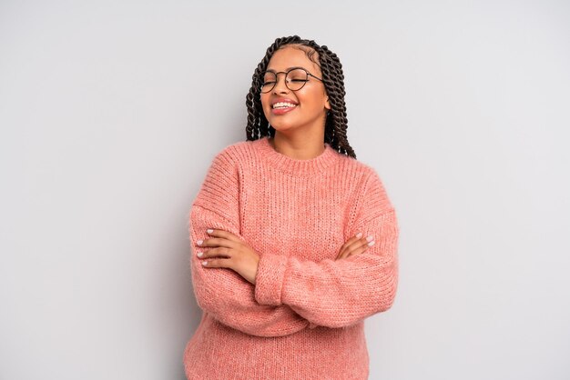 zwarte afro-vrouw die vrolijk lacht met gekruiste armen, met een ontspannen, positieve en tevreden pose