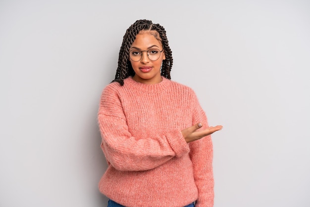 Zwarte afro-vrouw die vrolijk lacht, zich gelukkig voelt en een concept in kopieerruimte laat zien met handpalm