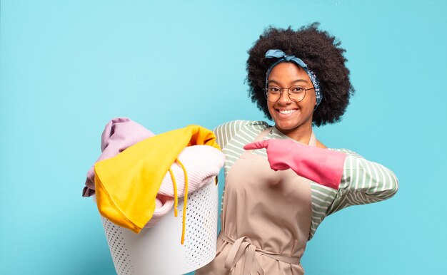 Zwarte afro-vrouw die vrolijk lacht, zich gelukkig voelt en naar de zijkant en naar boven wijst, object in kopie ruimte toont. huishoudelijk concept .. huishoudelijk concept