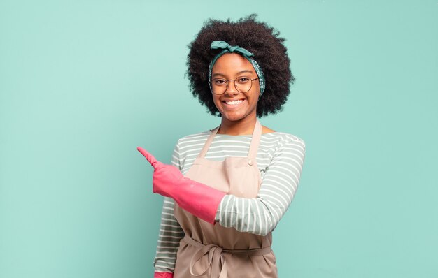 Zwarte afro-vrouw die vrolijk lacht, zich gelukkig voelt en naar de zijkant en naar boven wijst