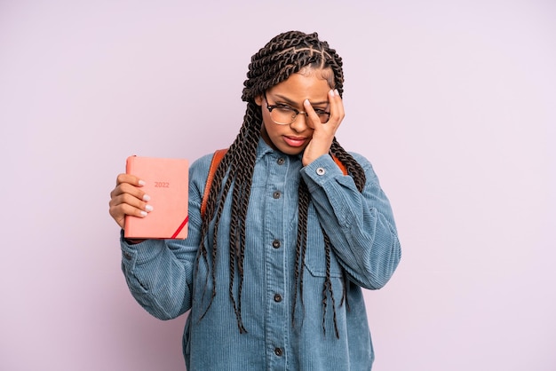 Zwarte afro-vrouw die zich verveeld, gefrustreerd en slaperig voelt na een vermoeiende studentenkalender of agendaconcept