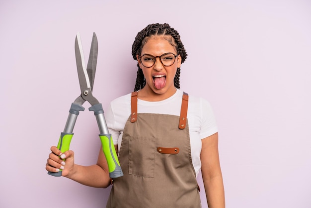 Zwarte afro vrouw met vrolijke en rebelse houding, grappen makend en tong uitsteken. tuinman of boer concept