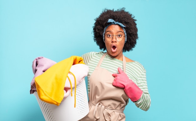 Zwarte afro vrouw op zoek geschokt en verrast met wijd open mond, wijzend naar zichzelf