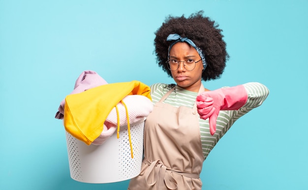 Zwarte afro-vrouw voelt zich boos boos geïrriteerd teleurgesteld of ontevreden met duimen naar beneden met een serieuze blik huishoudconcept huishoudelijk concept