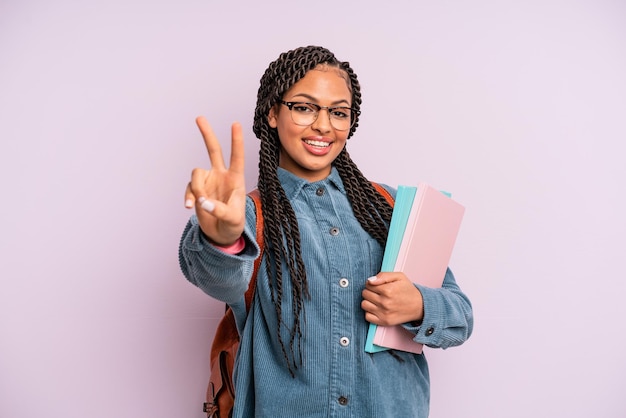 Zwarte afrovrouw die lacht en er gelukkig uitziet, gebarend naar overwinning of vrede. universitair studentenconcept