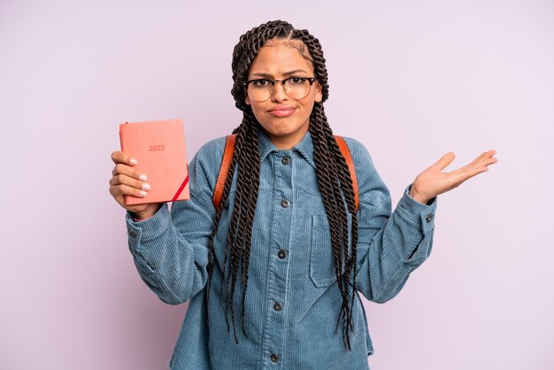 Zwarte afrovrouw die zich verward en verward en twijfelend voelt. studentenkalender of agendaconcept