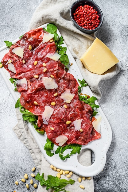 Zwarte angus rundercarpaccio met Parmezaanse kaas. Grijze achtergrond. Bovenaanzicht