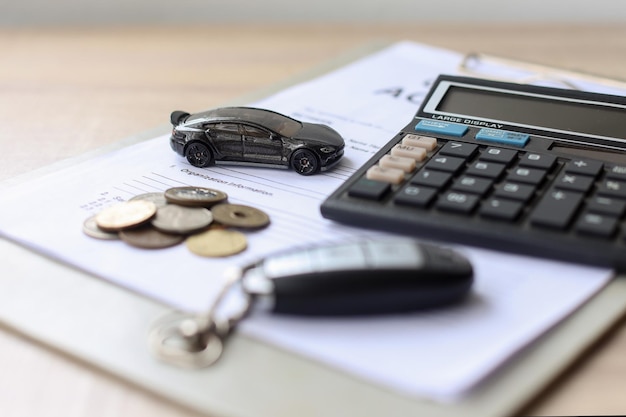 Zwarte auto en sleutel op leningdocument met munten en rekenmachine, geld besparen en financieren voor ca
