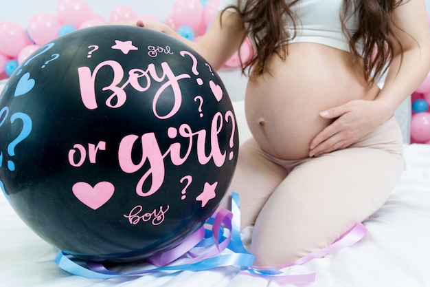 Zwarte ballon met de woorden meisje of jongen baby gender disclosure partij zwanger meisje met buik