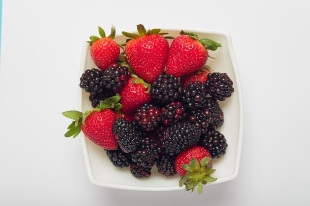 Zwarte bessen en aardbeien in een schaal op een witte achtergrond Seizoensfruit