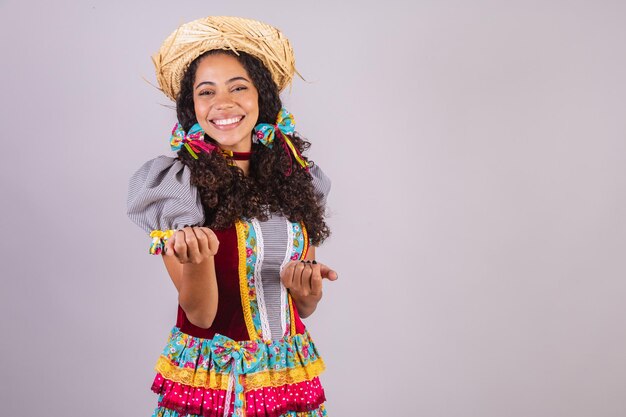 Zwarte Braziliaanse vrouw draagt verbroedering in juni-feestkleding in naam van Sao Joao Arraial, geweldig uitnodigend met handen