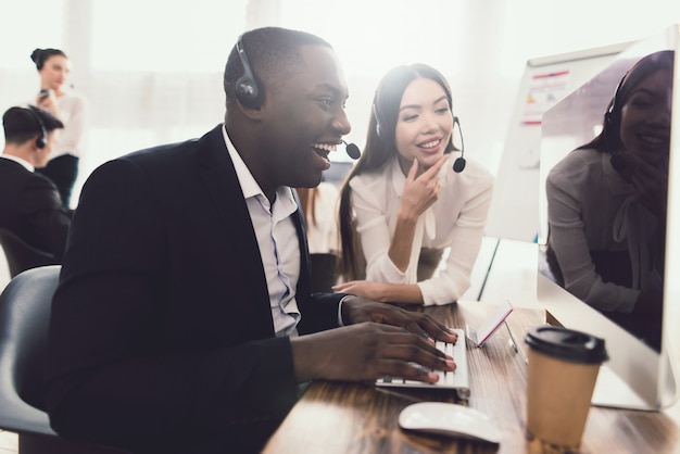 Zwarte call center operator kijkt op computerscherm.