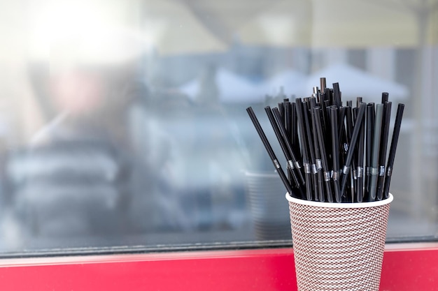 Zwarte cocktailbuizen met golf in een papieren beker voor een coffeeshopraam. Ruimte kopiëren