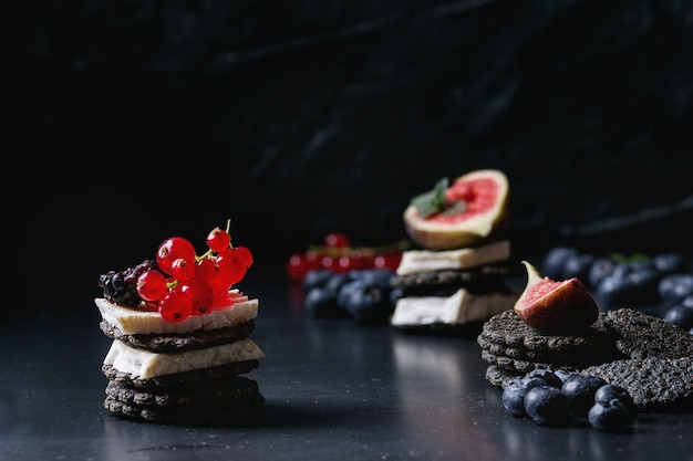 Foto zwarte crackers met kaas en bessen