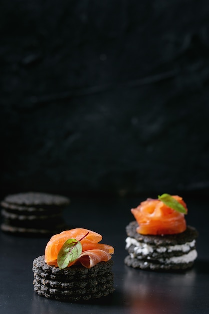 Zwarte crackers met zalm en bessen