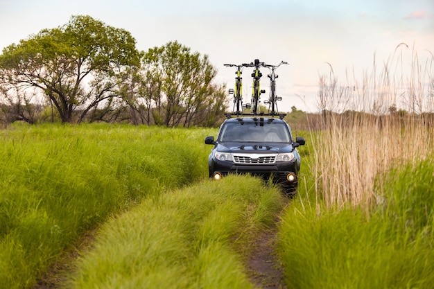 Foto zwarte crossover met drie fietsen op imperiaal op een onverharde weg