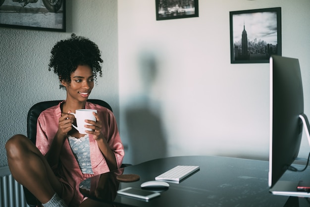 Zwarte die thuis met computer en koffie in de ochtend werkt