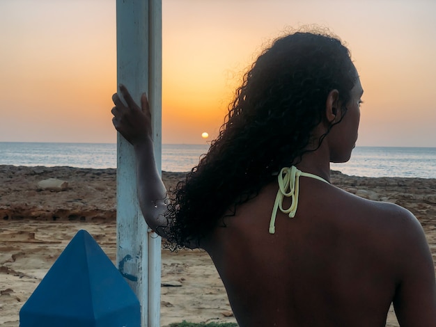 Zwarte die weg de zonsondergang op strand kijken