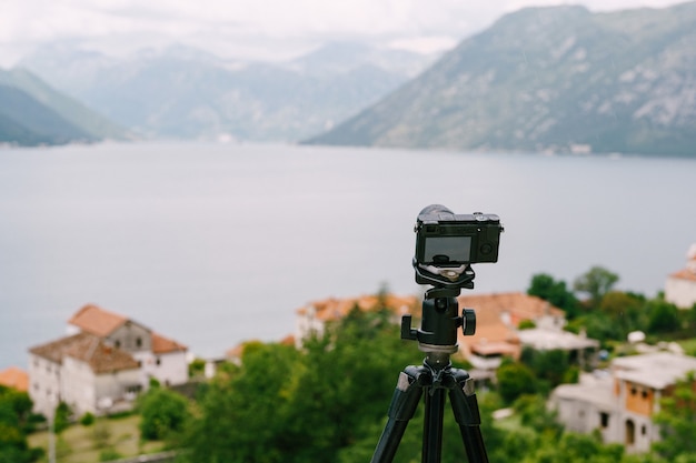 Zwarte digitale camera staat op een statief tegen het panorama van de stad en de bergen