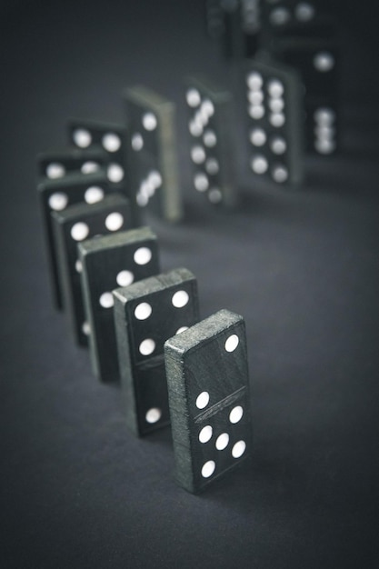 Zwarte dominostenen ketting op een donkere tafel achtergrond Domino-effect concept