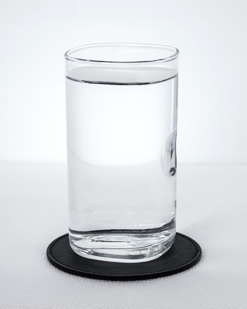 Foto zwarte drankonderleggers voor glazen met waterglas op witte achtergrond.