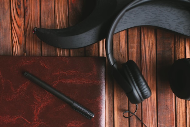 Zwarte elektrische gitaar, Kladblok en koptelefoon op een houten tafel. Muziekconcept maken.